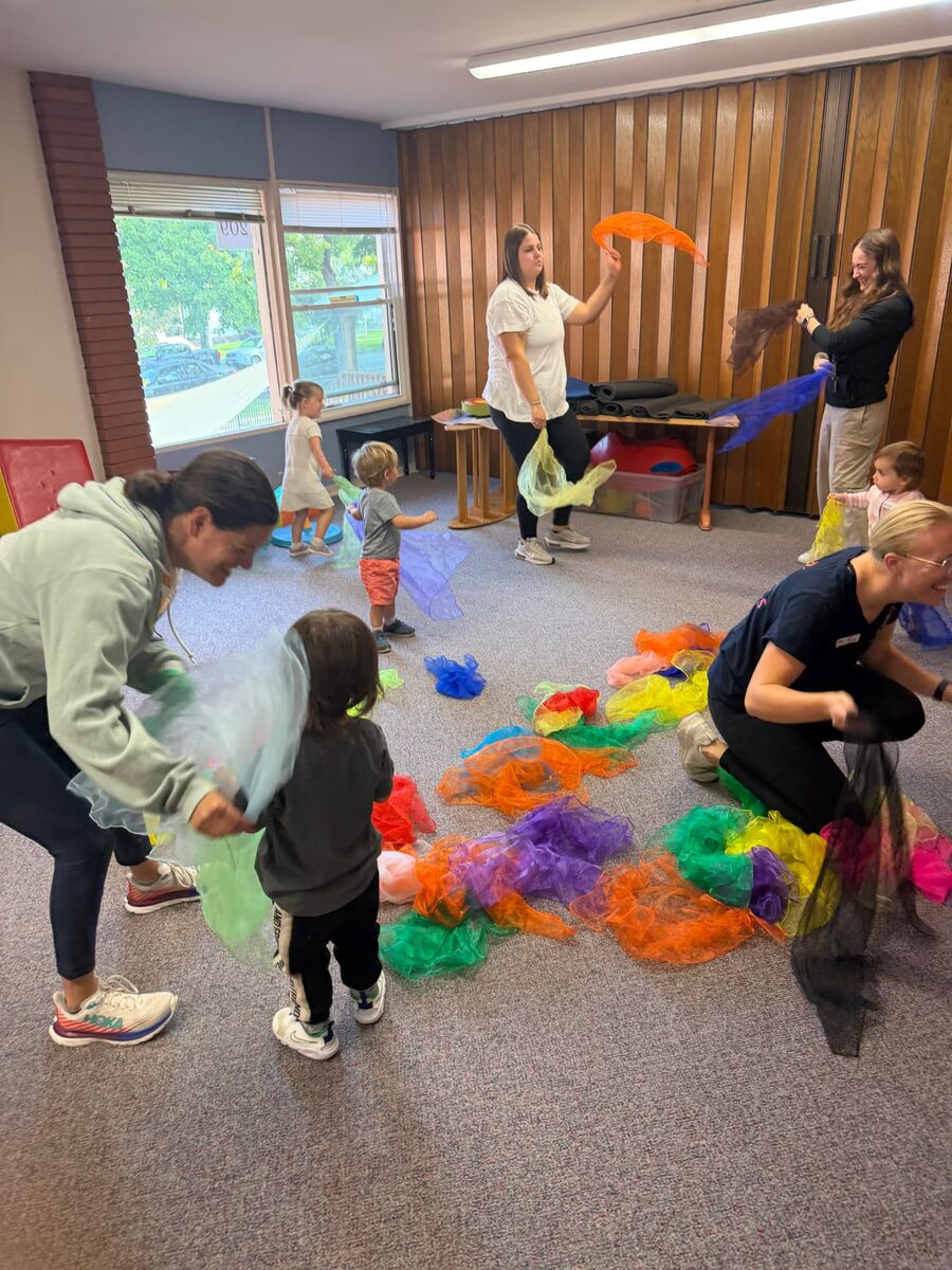 Learners and grown-ups move and play together with colorful scarves during music and movement